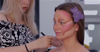 Profesyonel makyöz güzellik salonunda güzel bir genç kadın için makyaj yapıyor.                                   