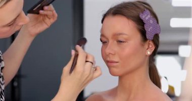 Profesyonel makyöz güzellik salonunda güzel bir genç kadın için makyaj yapıyor.                                   