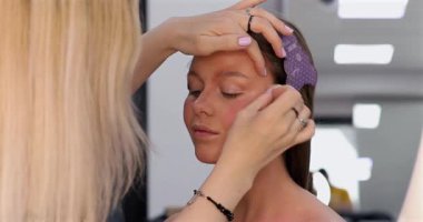 Profesyonel makyöz güzellik salonunda güzel bir genç kadın için makyaj yapıyor.                                   