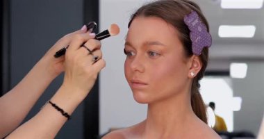 Profesyonel makyöz güzellik salonunda güzel bir genç kadın için makyaj yapıyor.                                   