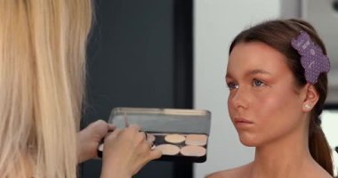 Profesyonel makyöz güzellik salonunda güzel bir genç kadın için makyaj yapıyor.                                   