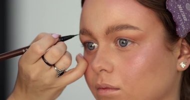 Profesyonel makyöz güzellik salonunda güzel bir genç kadın için makyaj yapıyor.                                   