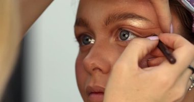Güzellik salonunda genç ve güzel bir kadına göz makyajı yapan profesyonel bir makyöz.                         