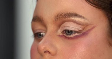 Güzellik salonunda genç ve güzel bir kadına göz makyajı yapan profesyonel bir makyöz.                         