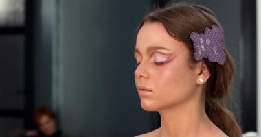 Güzellik salonunda genç ve güzel bir kadına göz makyajı yapan profesyonel bir makyöz.                         