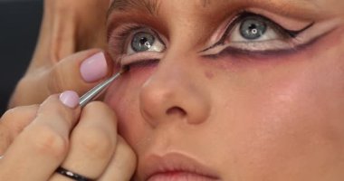 Güzellik salonunda genç ve güzel bir kadına göz makyajı yapan profesyonel bir makyöz.                         