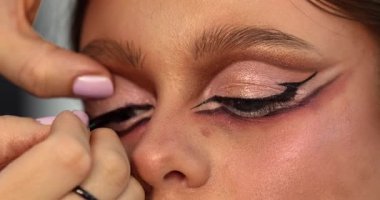 Güzellik salonunda genç ve güzel bir kadına göz makyajı yapan profesyonel bir makyöz.                         