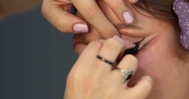 Güzellik salonunda genç ve güzel bir kadına göz makyajı yapan profesyonel bir makyöz.                         