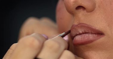 Profesyonel makyöz güzellik salonunda genç ve güzel bir bayana dudak makyajı yapıyor.                         
