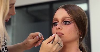 Güzellik salonunda genç ve güzel bir kadın için makyaj yapan profesyonel bir makyöz.            