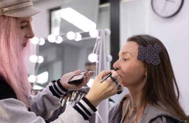 Profesyonel makyöz güzellik salonundaki güzel bayan modellere makyaj yapıyor..     