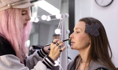 Profesyonel makyöz güzellik salonundaki güzel bayan modellere makyaj yapıyor..     