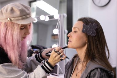 Profesyonel makyöz güzellik salonundaki güzel bayan modellere makyaj yapıyor..     