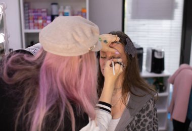 Profesyonel makyöz güzellik salonundaki güzel bayan modellere makyaj yapıyor..     