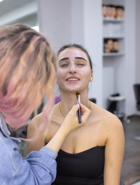 Profesyonel makyöz güzellik salonundaki güzel bayan modellere makyaj yapıyor..               
