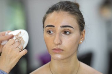 Profesyonel makyöz güzellik salonundaki güzel bayan modellere makyaj yapıyor..               