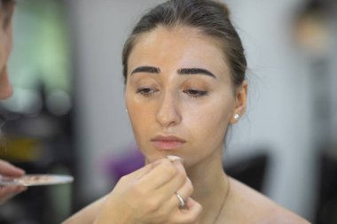 Profesyonel makyöz güzellik salonundaki güzel bayan modellere makyaj yapıyor..               