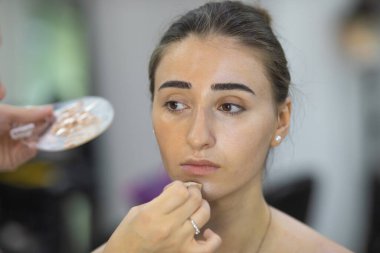 Profesyonel makyöz güzellik salonundaki güzel bayan modellere makyaj yapıyor..               
