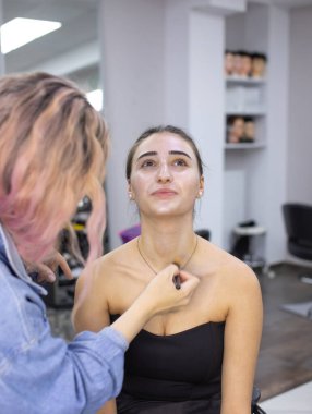 Profesyonel makyöz güzellik salonundaki güzel bayan modellere makyaj yapıyor..               