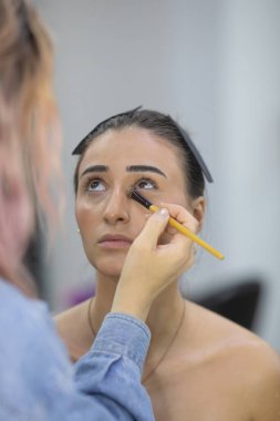 Profesyonel makyöz güzellik salonundaki güzel bayan modellere makyaj yapıyor..               