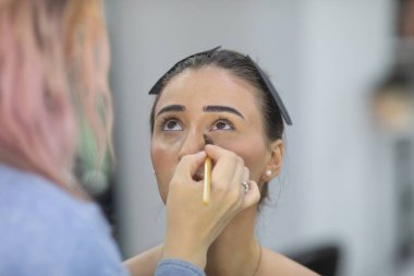 Profesyonel makyöz güzellik salonundaki güzel bayan modellere makyaj yapıyor..               