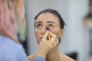 Profesyonel makyöz güzellik salonundaki güzel bayan modellere makyaj yapıyor..               