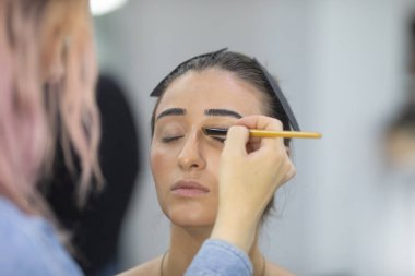 Profesyonel makyöz güzellik salonundaki güzel bayan modellere makyaj yapıyor..               