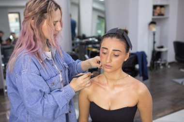 Profesyonel makyöz güzellik salonundaki güzel bayan modellere makyaj yapıyor..               