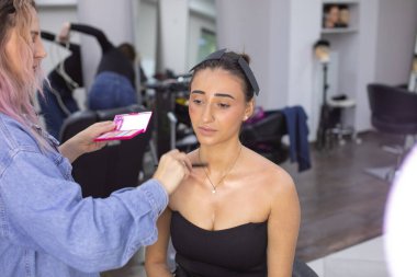 Profesyonel makyöz güzellik salonundaki güzel bayan modellere makyaj yapıyor..               
