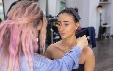 Profesyonel makyöz güzellik salonundaki güzel bayan modellere makyaj yapıyor..               