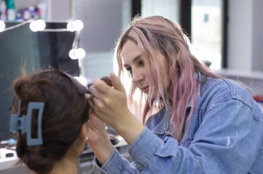 Profesyonel makyöz güzellik salonundaki güzel bayan modellere makyaj yapıyor..               