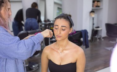 Profesyonel makyöz güzellik salonundaki güzel bayan modellere makyaj yapıyor..               