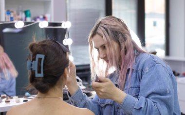 Profesyonel makyöz güzellik salonundaki güzel bayan modellere makyaj yapıyor..               