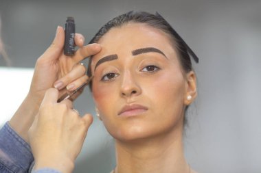 Profesyonel makyöz güzellik salonundaki güzel bayan modellere makyaj yapıyor..               