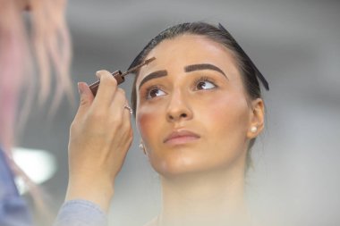 Profesyonel makyöz güzellik salonundaki güzel bayan modellere makyaj yapıyor..               