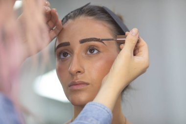 Profesyonel makyöz güzellik salonundaki güzel bayan modellere makyaj yapıyor..               