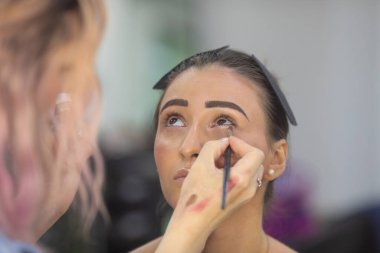 Profesyonel makyöz güzellik salonundaki güzel bayan modellere makyaj yapıyor..               