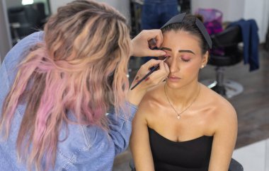 Profesyonel makyöz güzellik salonundaki güzel bayan modellere makyaj yapıyor..               
