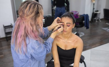 Profesyonel makyöz güzellik salonundaki güzel bayan modellere makyaj yapıyor..               