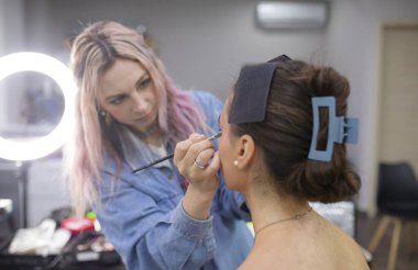 Profesyonel makyöz güzellik salonundaki güzel bayan modellere makyaj yapıyor..               