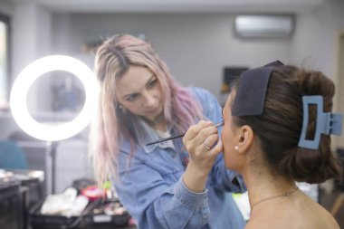 Profesyonel makyöz güzellik salonundaki güzel bayan modellere makyaj yapıyor..               