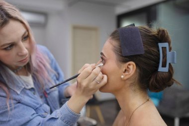 Profesyonel makyöz güzellik salonundaki güzel bayan modellere makyaj yapıyor..               