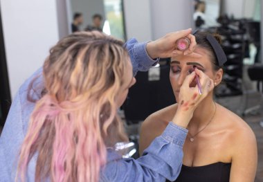 Profesyonel makyöz güzellik salonundaki güzel bayan modellere makyaj yapıyor..               