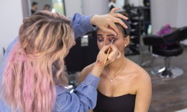 Profesyonel makyöz güzellik salonundaki güzel bayan modellere makyaj yapıyor..               