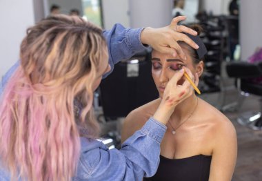 Profesyonel makyöz güzellik salonundaki güzel bayan modellere makyaj yapıyor..               