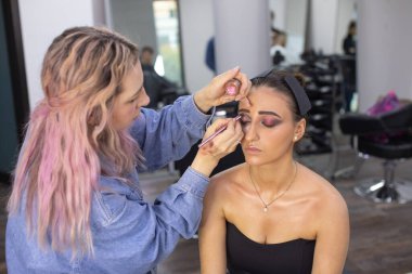 Profesyonel makyöz güzellik salonundaki güzel bayan modellere makyaj yapıyor..               