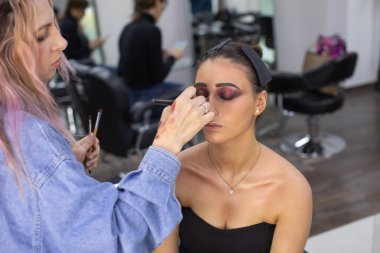 Profesyonel makyöz güzellik salonundaki güzel bayan modellere makyaj yapıyor..               