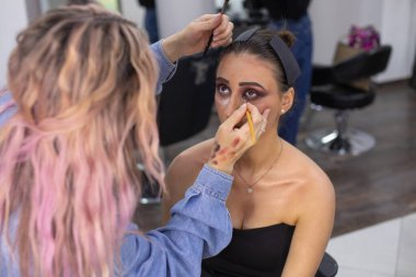 Profesyonel makyöz güzellik salonundaki güzel bayan modellere makyaj yapıyor..               