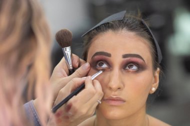 Profesyonel makyöz güzellik salonundaki güzel bayan modellere makyaj yapıyor..               