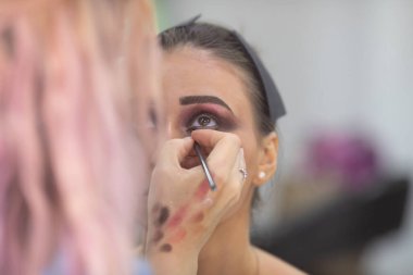 Profesyonel makyöz güzellik salonundaki güzel bayan modellere makyaj yapıyor..               